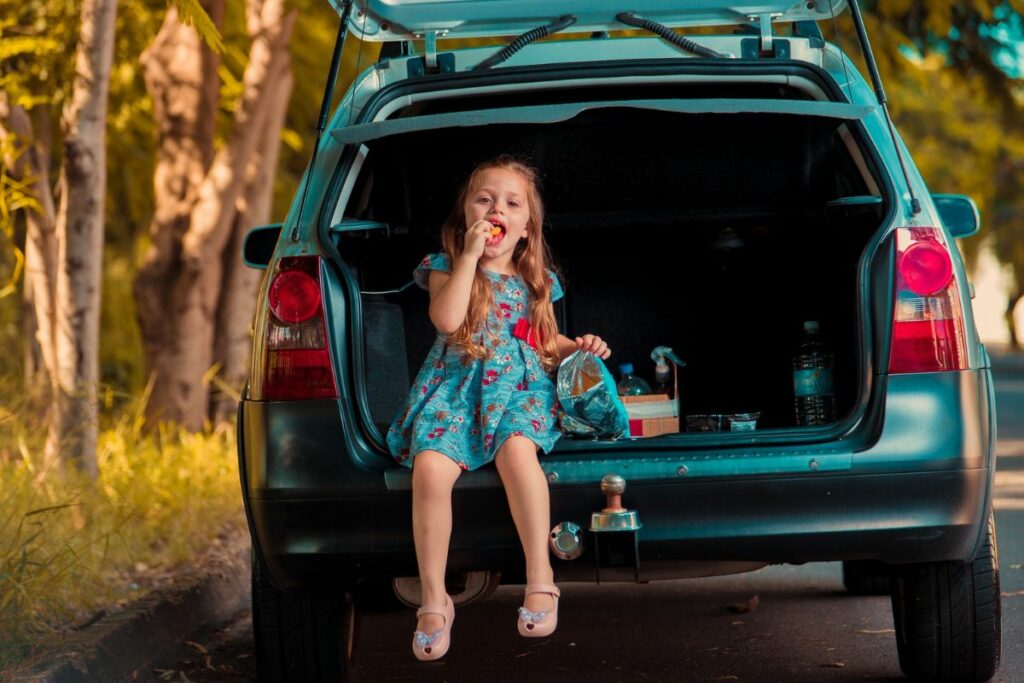 Little girl eating on car